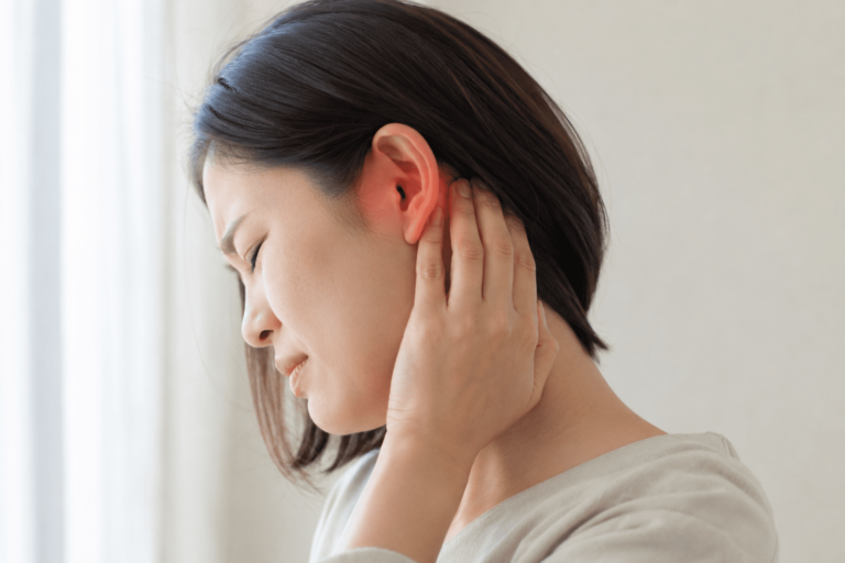 女性が耳の後ろ〜首を手で押さえ、痛みで目を閉じている