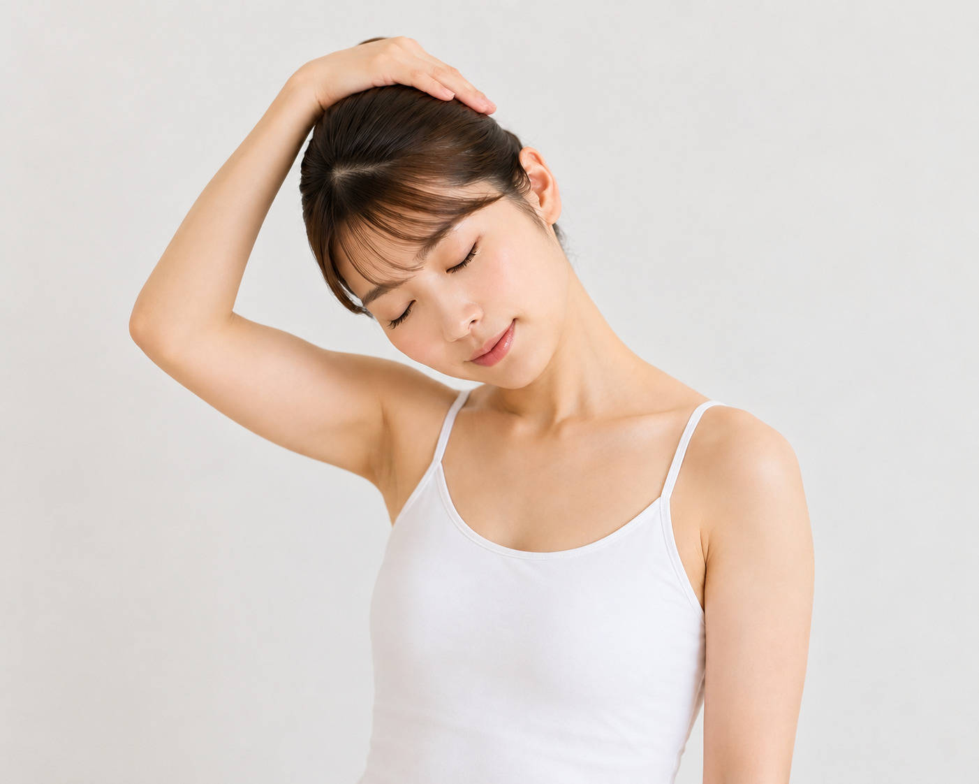 頭に手を添えて首筋を伸ばすストレッチをする白いタンクトップ姿の女性